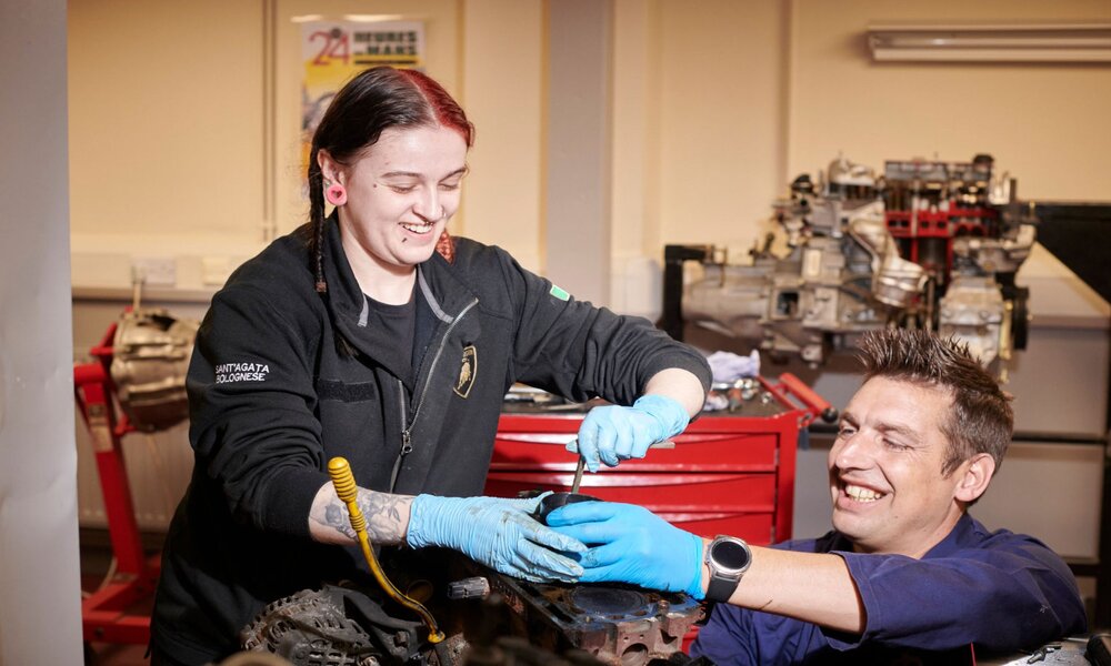 An automotive apprentice and tutor working together on a car in our training facility