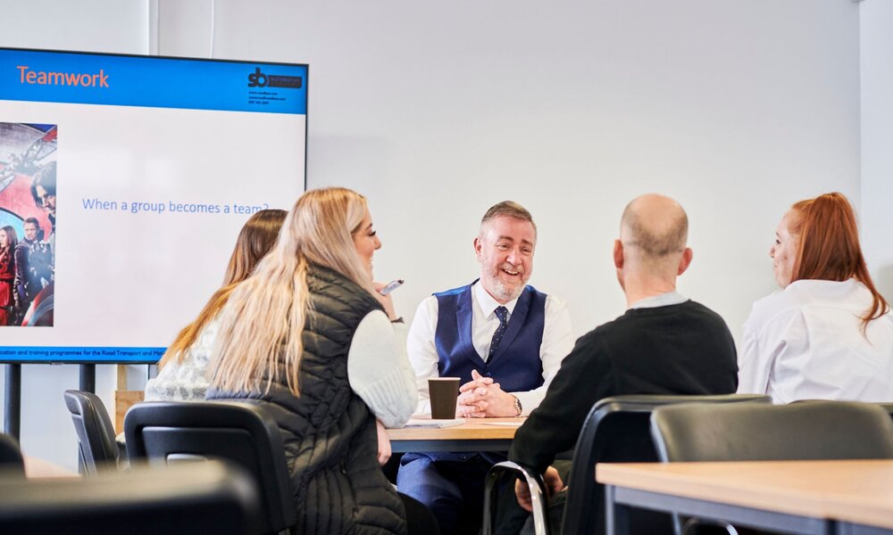 An S&B Academy Business Apprenticeship teacher laughing in a classroom with students